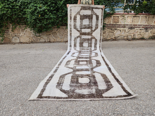 3x10 white Turkish runner with dark looping geometric motifs and a narrow border, draped outdoors
