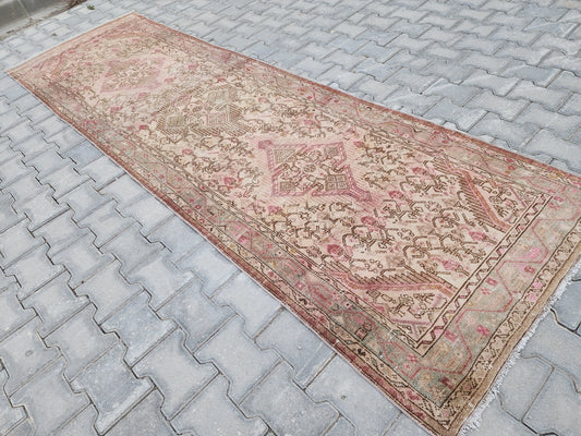 3x10 Turkish runner in faded beige and pink with repeating geometric medallions, shown outdoors