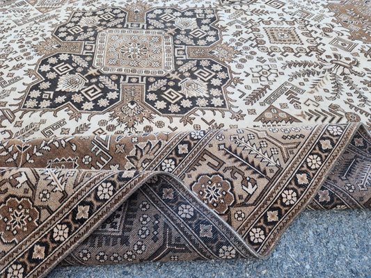 Folded corner of a 10x13 brown and ivory vintage wool rug showing a dark central medallion, patterned border and underside