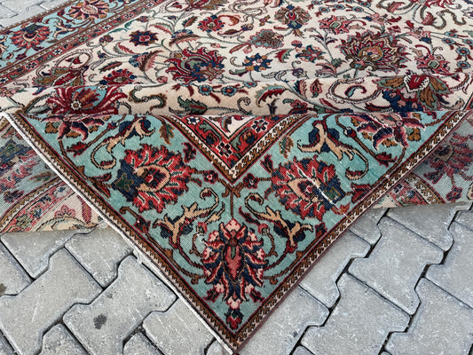 Corner detail of a Turkish wool-cotton rug with an ivory field, muted green border and red floral motifs