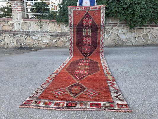 3x11 vintage Herki wool runner with red and brown geometric medallions and a pale zigzag border